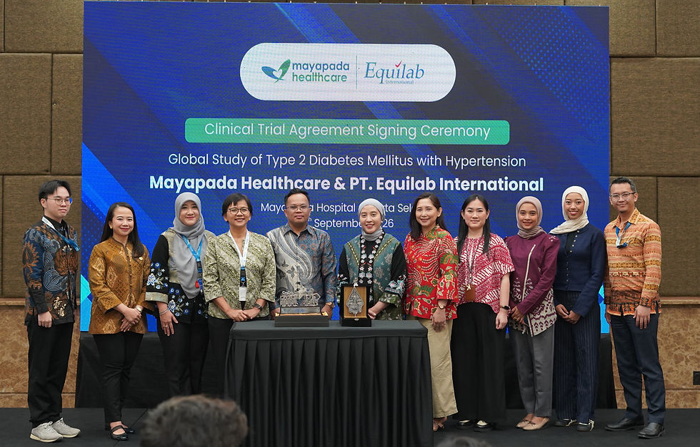Group posing at a clinical trial signing ceremony, with a blue banner reading Mayapada Healthcare and Equilab International behind them.