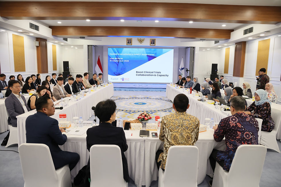 International meeting in a bright conference room, people seated around U-shaped tables facing a screen on clinical trials.
