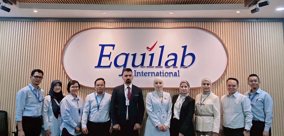 Ten employees pose in a lobby under an Equilab International sign, wearing business attire and ID badges.